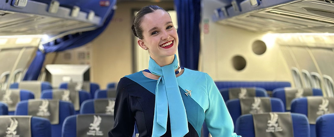 Alumna TCP en un avión sonriente. Con el unforme de azafatad de vuelo.