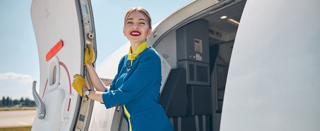 Azafata de vuelo dando la bienvenida desde la puerta del avión