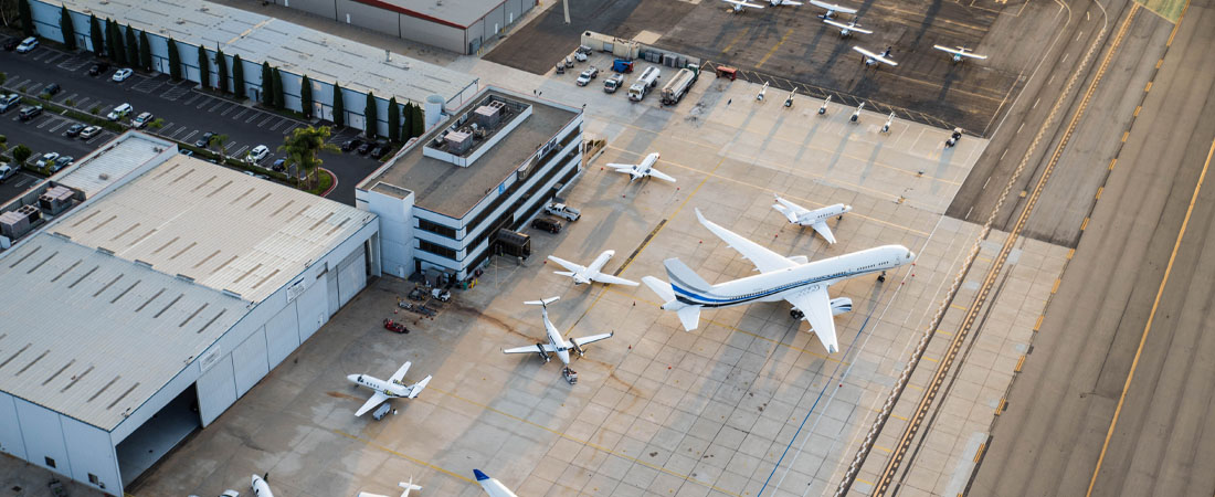 Vista aérea de aviones privados estacionados en una plataforma aeroportuaria junto a hangares