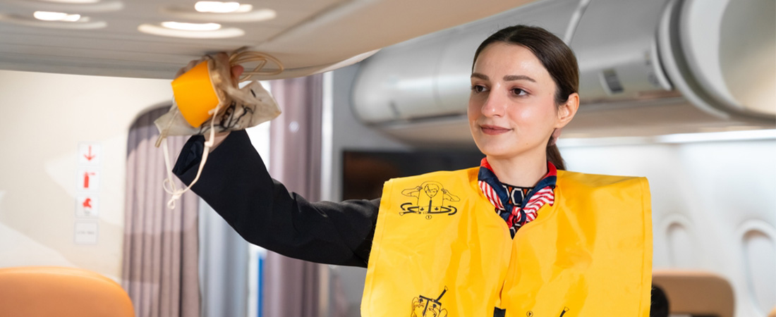 Azafata de vuelo mostrando cómo colocarse una mascarilla de oxígeno durante una demostración de seguridad en el avión.