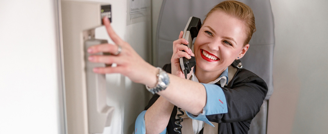 Azafata de vuelo hablando por teléfono durante un vuelo.